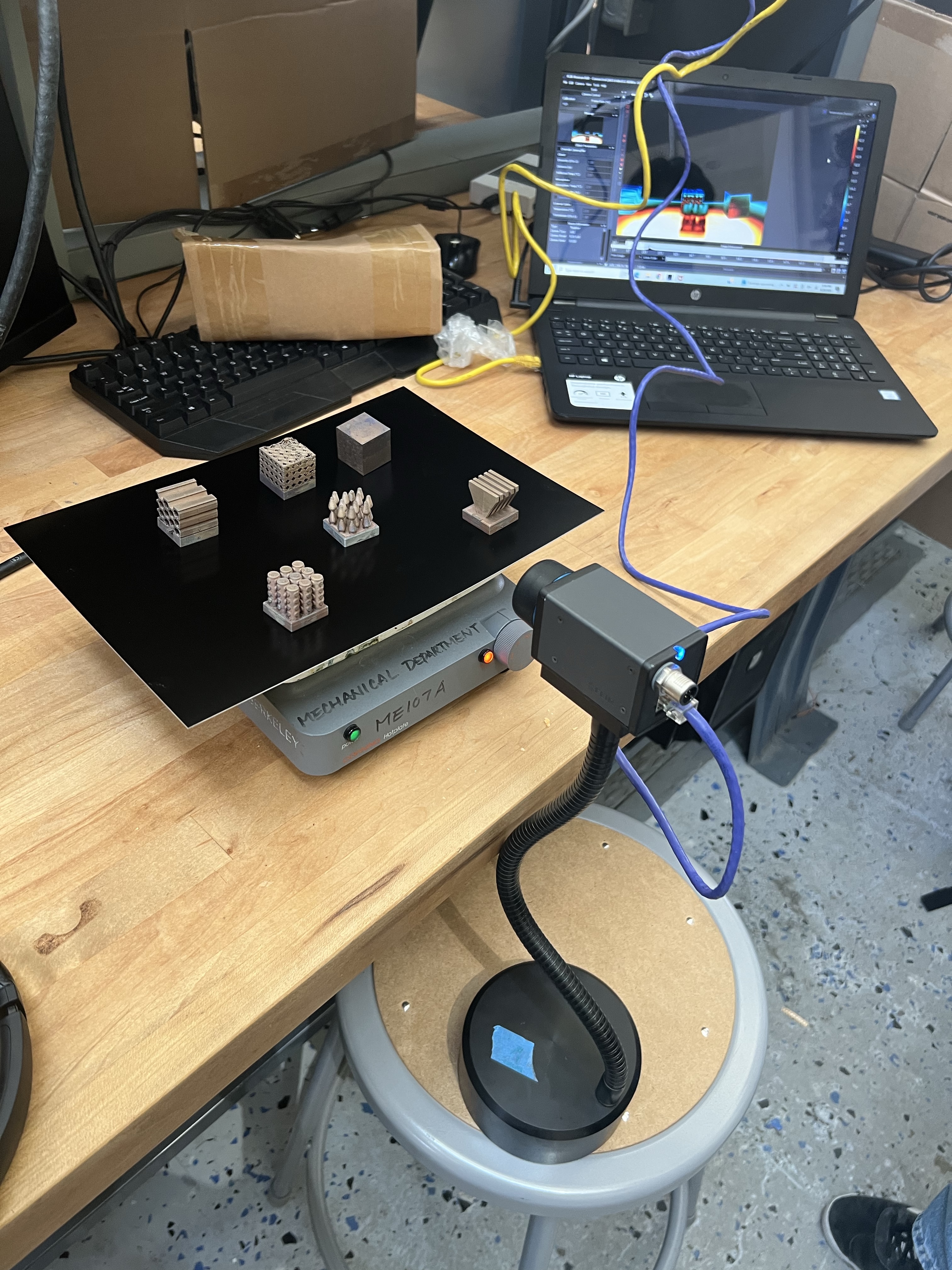 Metal heat sinks on a hot plate with a thermal camera and laptop displaying infrared measurements