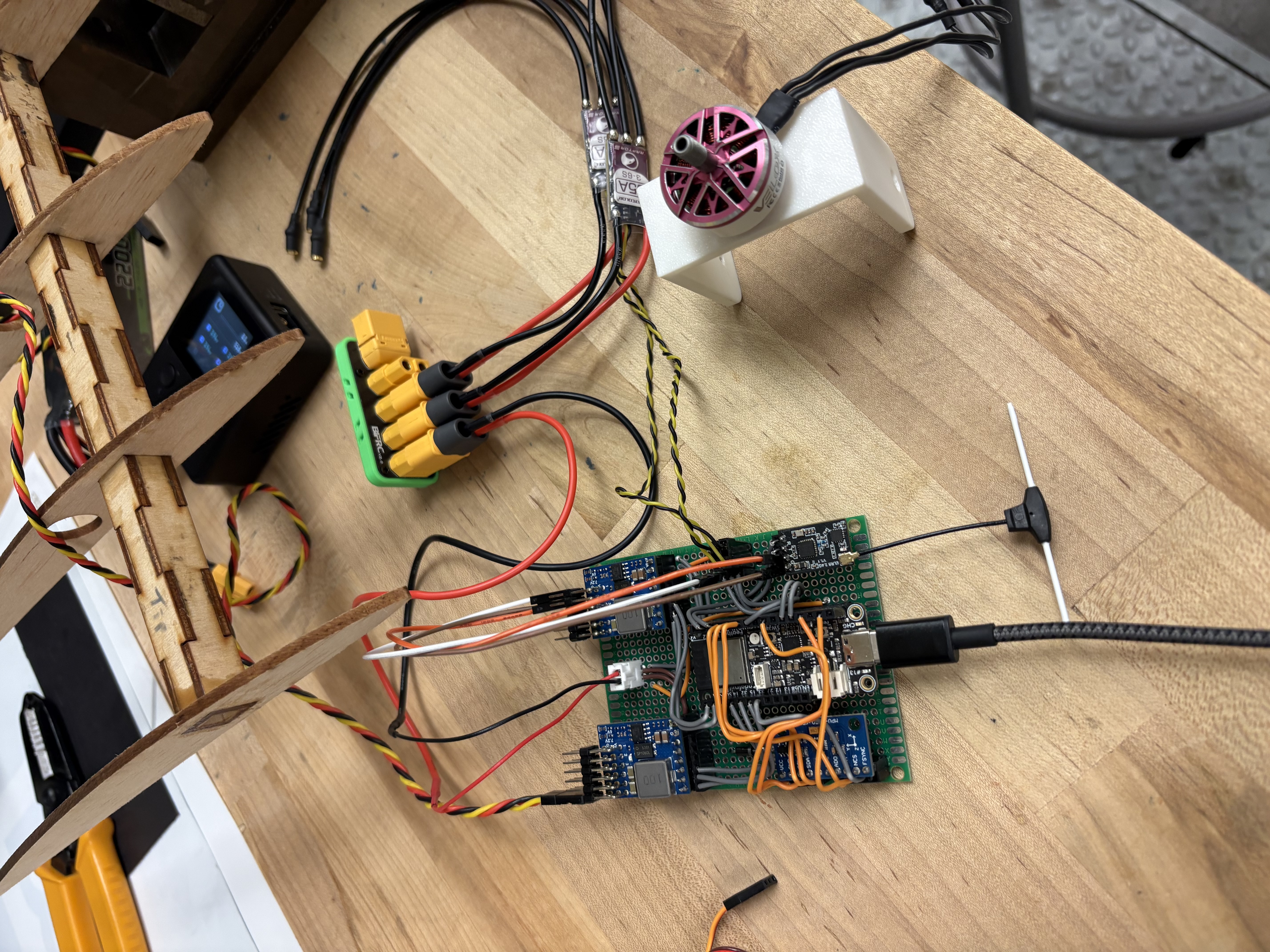 Flight computer on a protoboard connected to power distribution, ESCs, and a brushless motor on the workbench